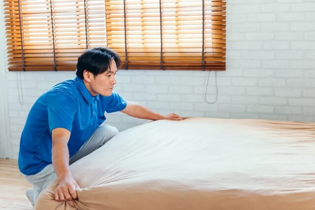 ベッドを整える男性