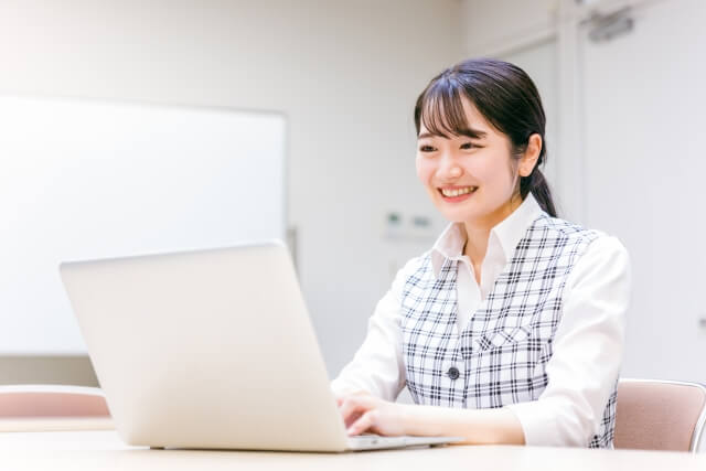 オフィスで微笑む女性とノートパソコン