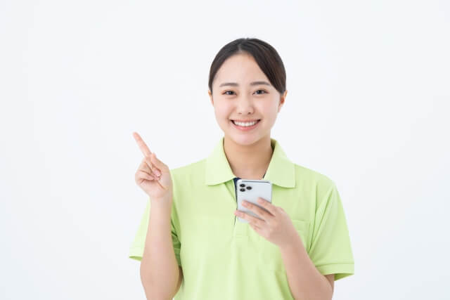 スマートフォンを持ち指差す笑顔の女性