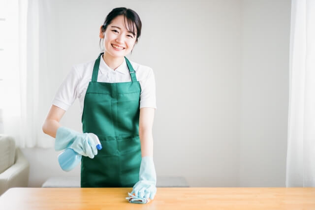 テーブルを掃除するエプロン姿の女性