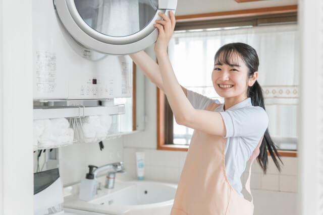 洗濯機に洗濯物を入れる女性