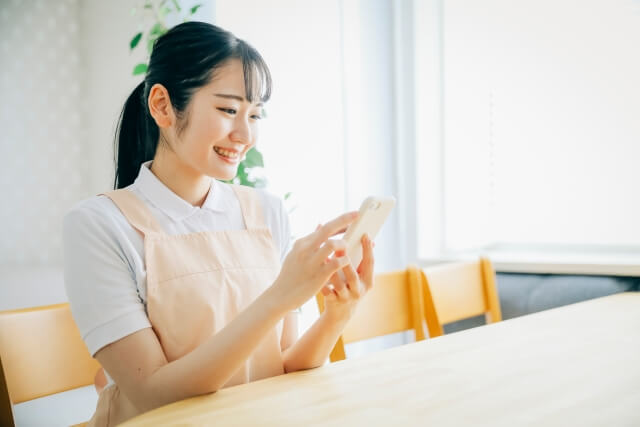 テーブルに座りスマートフォンを操作する女性